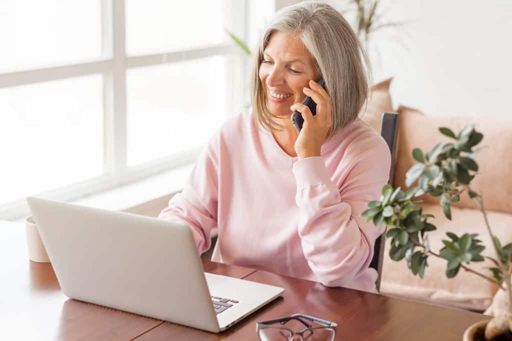 Mature woman on the phone while using laptop