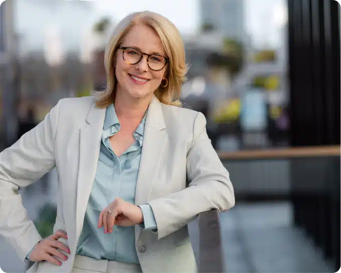 Middle-aged businesswoman in light suit resting arm against railing