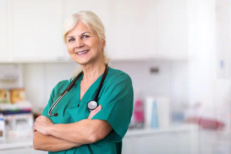 Senior female healthcare professional with stethoscope smiling at camera