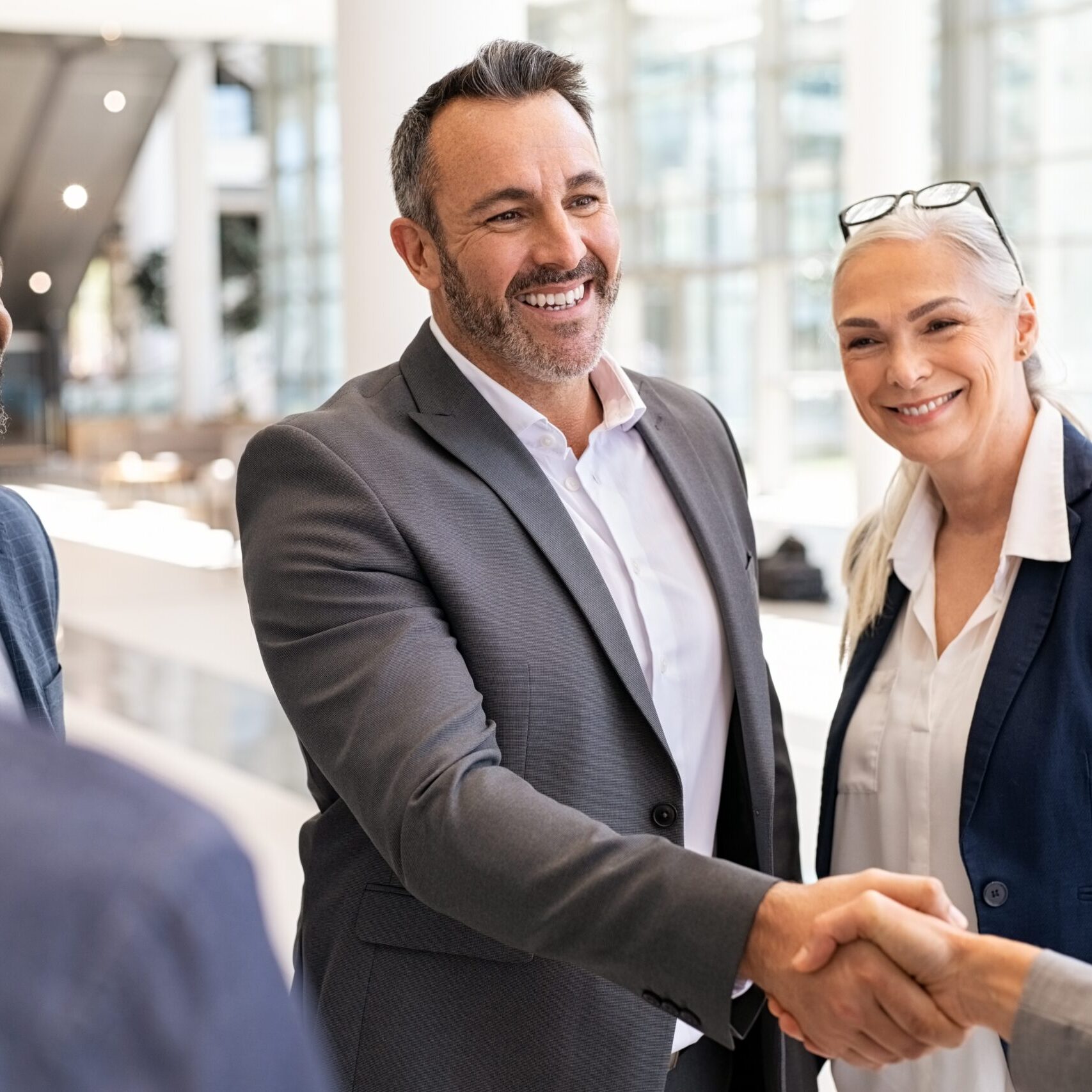 Mature businessman shaking hands with young woman in group